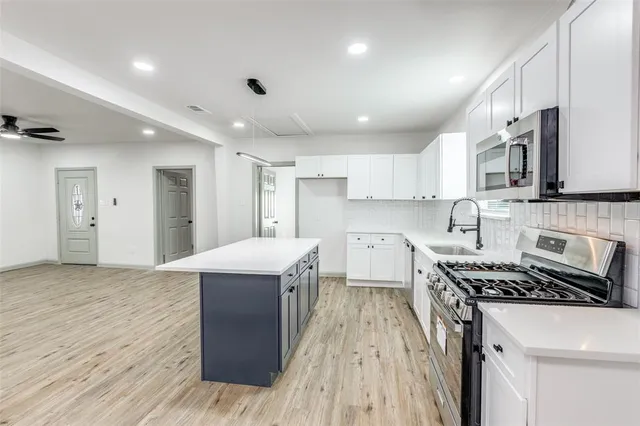 a kitchen with kitchen island stainless steel appliances a sink stove and refrigerator