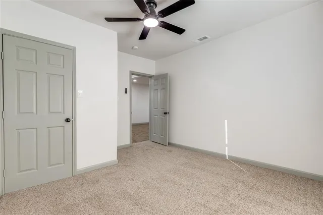 an empty room with closet and a ceiling fan
