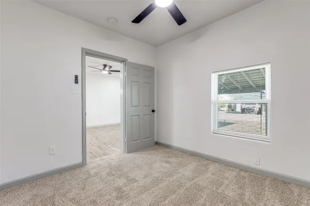 an empty room with chandelier fan and windows