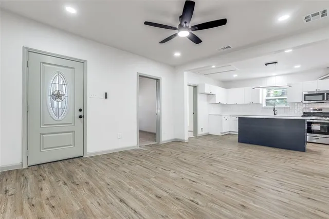 a view of kitchen and empty room with wooden floor