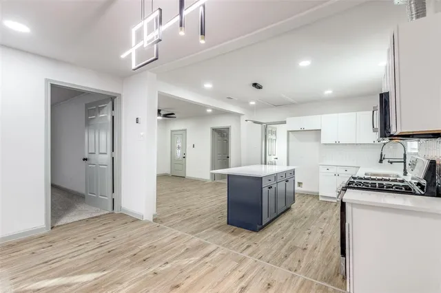 a kitchen with granite countertop a stove top oven a sink dishwasher a refrigerator and a dining table with wooden floor