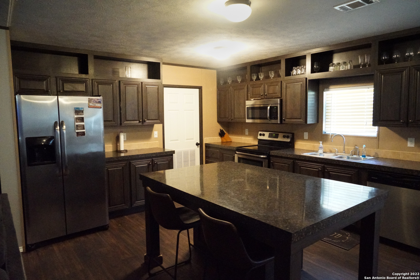 10179 Commerce Street Atascosa, TX 78002 - Photo 6 of 12 a large kitchen with a table chairs refrigerator and sink
