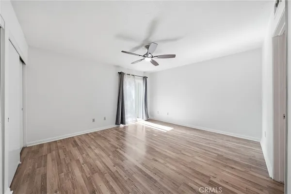 a view of a room with wooden floor and a ceiling fan