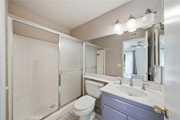 a bathroom with a toilet a sink a mirror a shower a vanity and window