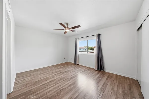 a view of a room with wooden floor and a ceiling fan