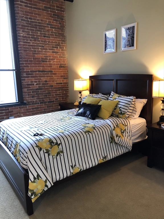 55 Green Street, Unit D105 Clinton, MA 01510 - Photo 6 of 18 a bedroom with a bed and a lamp