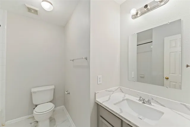 a bathroom with a granite countertop sink a toilet and a mirror