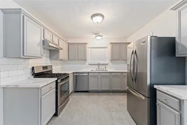 a kitchen with stainless steel appliances granite countertop a refrigerator sink and stove