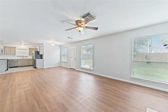 a view of empty room with wooden floor and fan