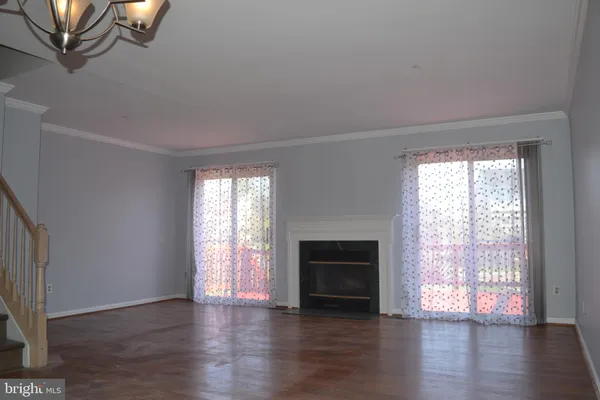 an empty room with wooden floor fireplace and windows