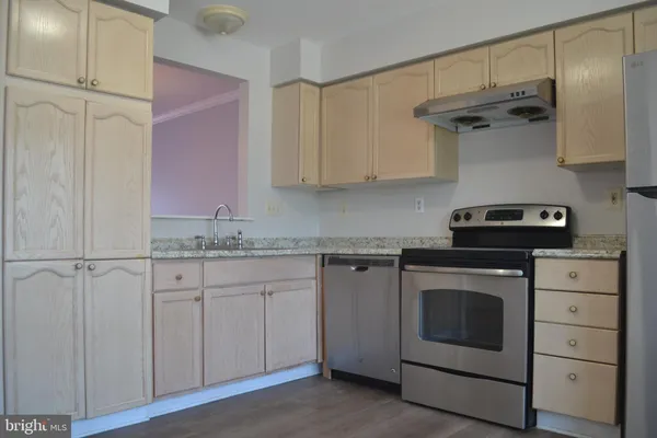 a kitchen with cabinets appliances and a wooden floor