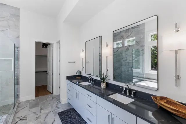 a spacious bathroom with a double vanity sink a mirror and a shower