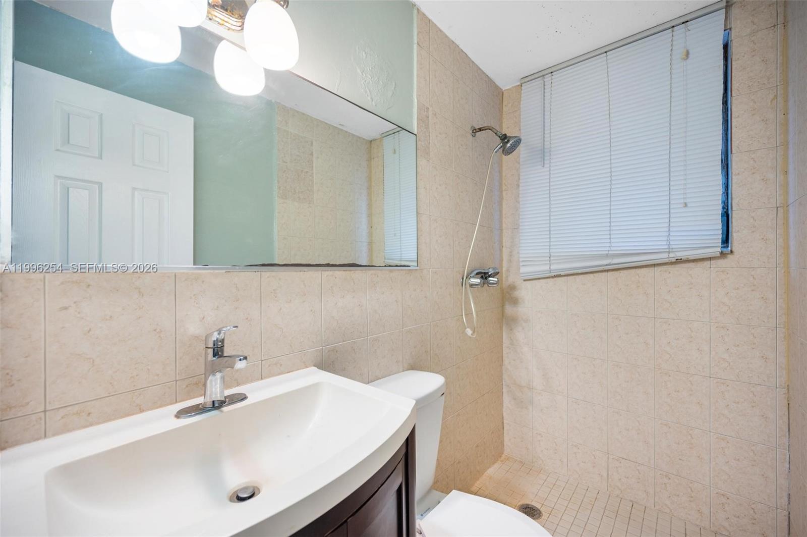 825 Alton Road, Unit 2 Miami Beach, FL 33139 - Photo 5 of 8 a bathroom with a sink a toilet and shower