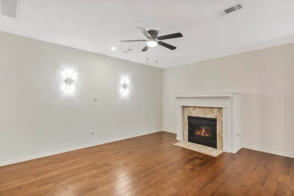 an empty room with wooden floor fireplace and a window