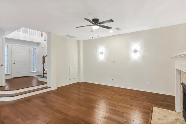 a view of empty room with wooden floor and ceiling fan