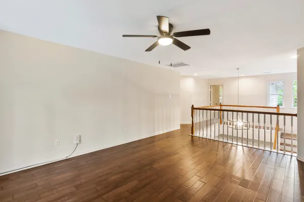 a view of a room with wooden floor fan and windows