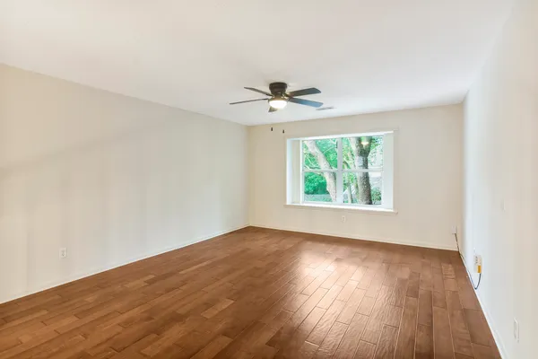 an empty room with wooden floor and windows