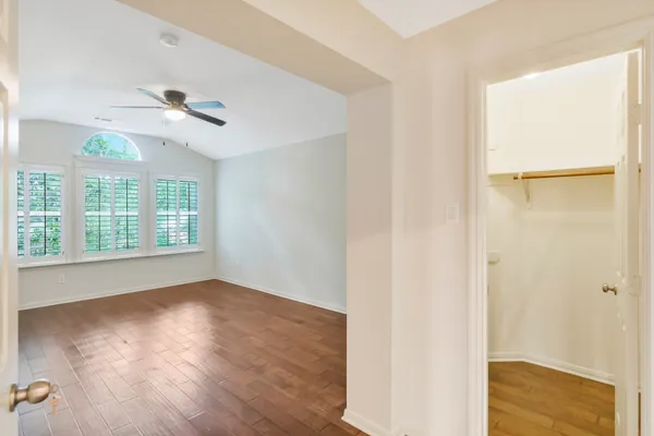 a view of an empty room with wooden floor and a window