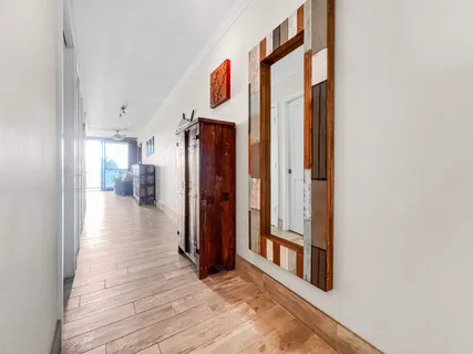 a view of a hallway with wooden floor and a bathroom