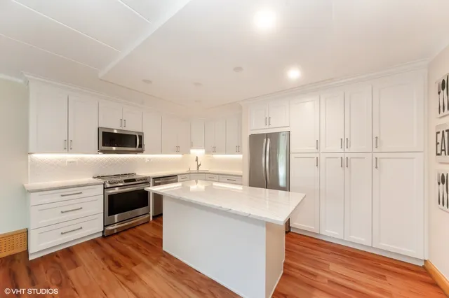 a kitchen with stainless steel appliances granite countertop a stove a sink dishwasher a refrigerator and a microwave oven with wooden floor