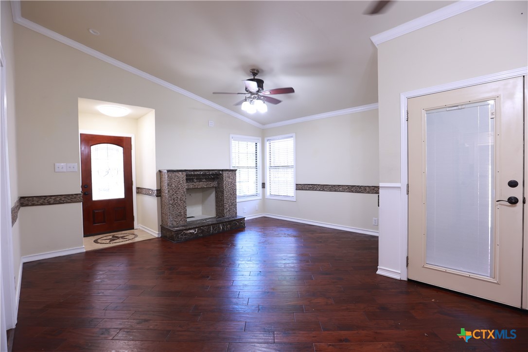 2706 Bowie Trail Temple, TX 76502 - Photo 16 of 25 an empty room with wooden floor a ceiling fan and a fireplace