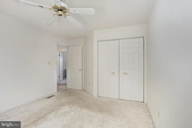 a view of a white house next to a yard with large trees