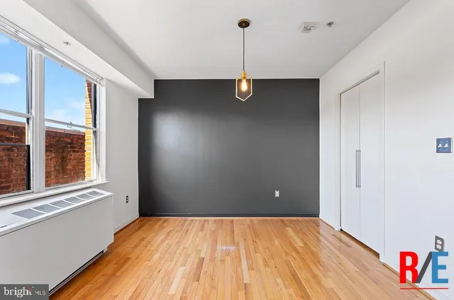 a view of an empty room with a window and wooden floor