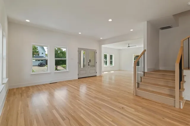 a view of an empty room with wooden floor and a window