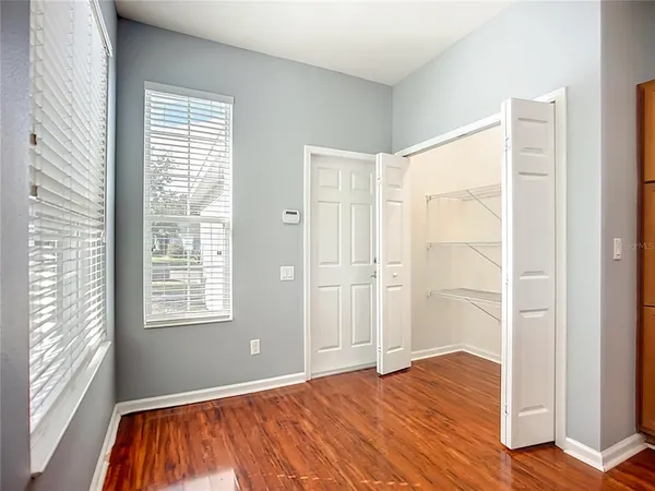 a view of an empty room with wooden floor and a window