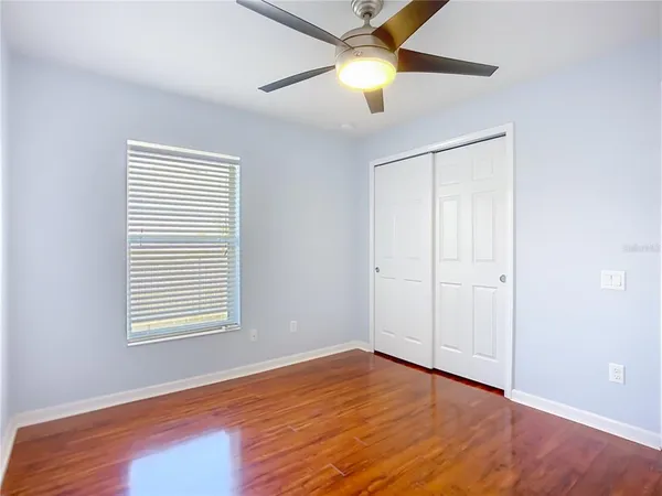 an empty room with wooden floor closet and windows