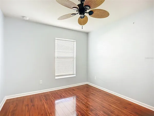 an empty room with wooden floor fan and windows