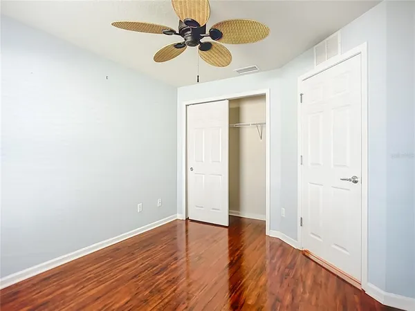 an empty room with wooden floor fan and windows