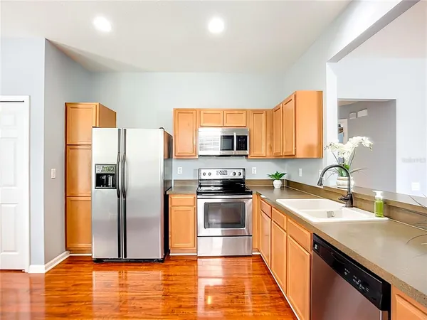 a kitchen with stainless steel appliances granite countertop a refrigerator a sink and a stove