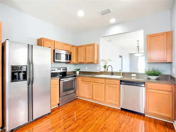 a kitchen with stainless steel appliances granite countertop a refrigerator a stove top oven a sink and dishwasher with wooden floor