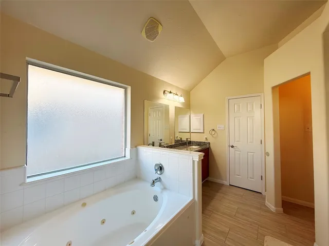a large bathroom with a tub a sink and a large mirror