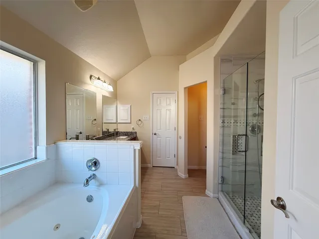 a bathroom with a tub a sink and a large mirror