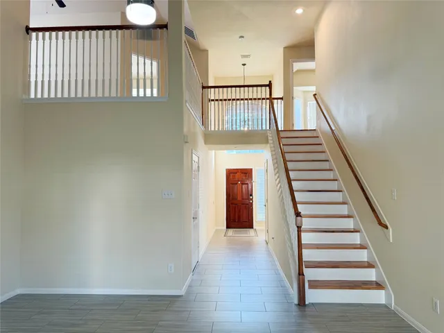 a view of a hallway with wooden floor and stairs