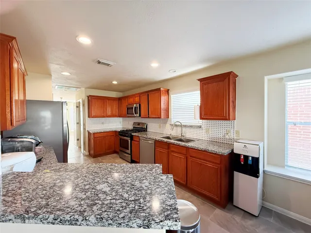 a large kitchen with stainless steel appliances kitchen island granite countertop a sink and cabinets
