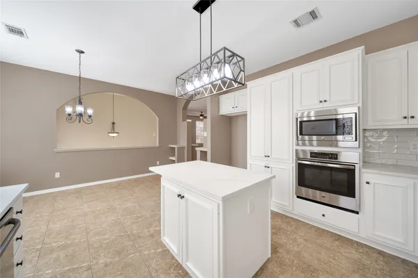 a kitchen that has a lot of cabinets and stainless steel appliances