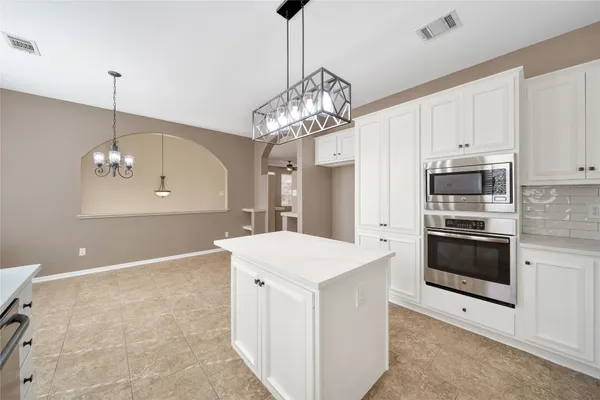 a kitchen that has a lot of cabinets and stainless steel appliances