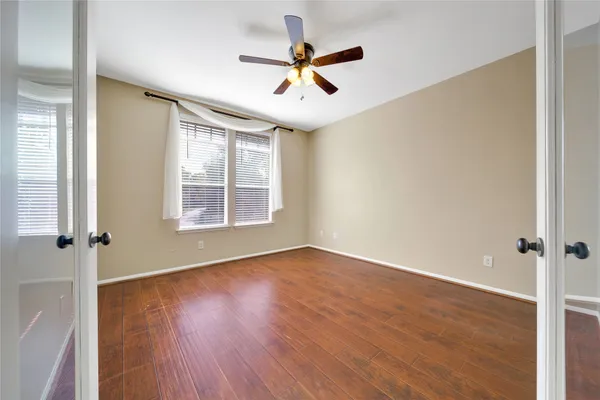 an empty room with wooden floor fan and windows