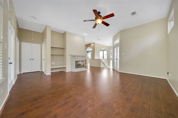 a view of empty room with wooden floor and fan
