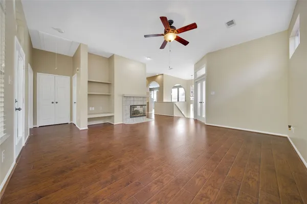 a view of empty room with wooden floor and fan