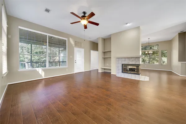 an empty room with wooden floor fireplace and windows