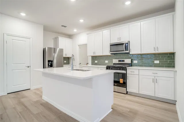 a kitchen with stainless steel appliances granite countertop a sink and a stove