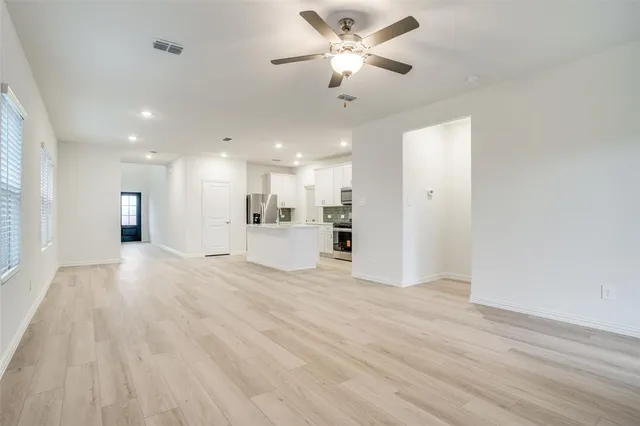 a view of empty room with wooden floor and ceiling fan