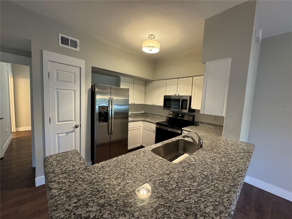10000 Southwest 52nd Avenue, Unit 139 Gainesville, FL 32608 - Photo 2 of 16 a kitchen with granite countertop a refrigerator and a sink