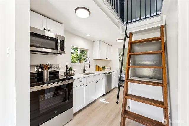 a kitchen with stainless steel appliances white cabinets and a stove top oven
