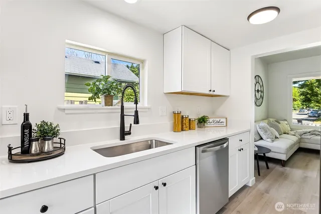 a kitchen with a sink dishwasher and white cabinets