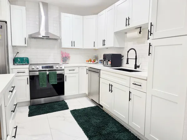 a kitchen with white cabinets and appliances
